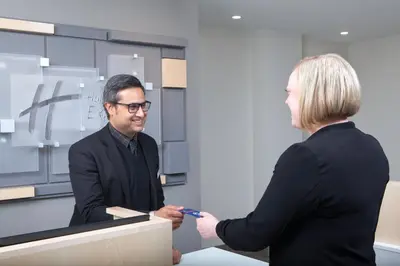 a man and a woman shaking hands in an office at Holiday Inn Express & Suites Mississauga-Toronto Southwest by IHG in Mississauga