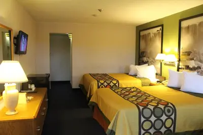 a hotel room with two beds and a desk at Super 8 by Wyndham Niagara Falls North in Niagara Falls