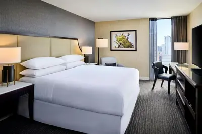 a hotel room with a large white bed and a desk at Sheraton Hamilton Hotel in Hamilton