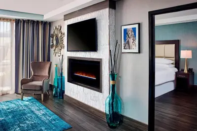 a room with a fireplace and a chair and a television at Sheraton Hamilton Hotel in Hamilton