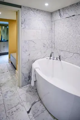 a white bath tub in a bathroom with marble walls at Sheraton Hamilton Hotel in Hamilton