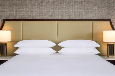 a bed with white pillows and two lamps at Sheraton Hamilton Hotel in Hamilton