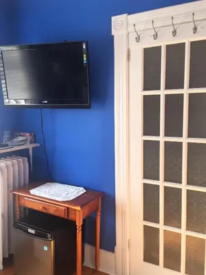 a room with a table and a tv on a blue wall at Ellis House Bed & Breakfast in Niagara Falls
