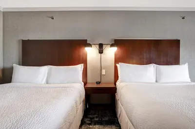 two beds in a hotel room with white sheets at Four Points by Sheraton Toronto Mississauga in Mississauga