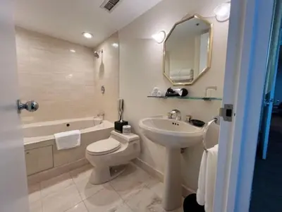 a bathroom with a sink and a toilet and a tub at Cambridge Suites Toronto in Toronto