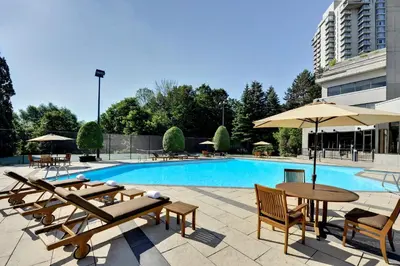 a pool with tables and umbrellas next to a building at Crowne Plaza Toronto - North York by IHG in Toronto