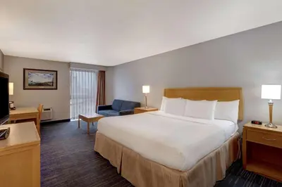 a hotel room with a large bed and a chair at Days Inn by Wyndham Niagara Falls Near The Falls in Niagara Falls