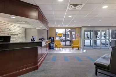 an office lobby with yellow chairs and a counter at Days Inn by Wyndham Niagara Falls Near The Falls in Niagara Falls