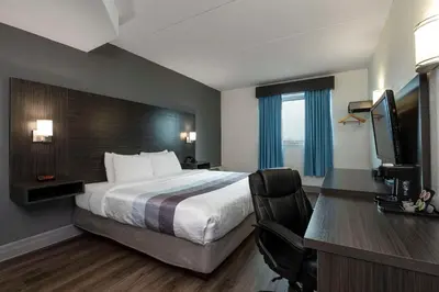 a hotel room with a bed and a desk with a television at Comfort Hotel in Niagara Falls