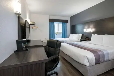 a hotel room with two beds and a desk at Comfort Hotel in Niagara Falls