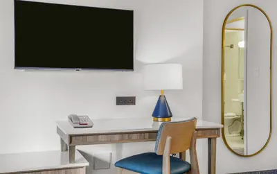 a desk with a blue chair and a mirror at Travelodge by Wyndham Niagara Falls At the Falls in Niagara Falls