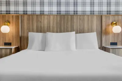 a bed with white pillows in a room at Travelodge by Wyndham Niagara Falls At the Falls in Niagara Falls
