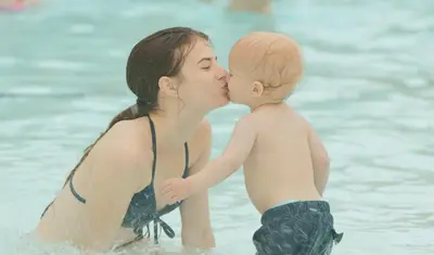 a woman kissing a baby in the water at Americana Waterpark Resort & Spa in Niagara Falls