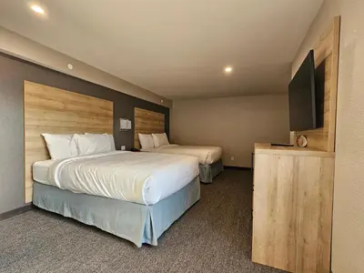 a hotel room with two beds and a flat screen tv at Vittoria Hotel & Suites in Niagara Falls
