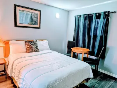 a bedroom with a bed and a table and a window at A1 Inn Niagara Falls in Niagara Falls