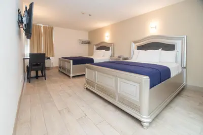 a hotel room with two beds and a desk at Diplomat Inn in Niagara Falls