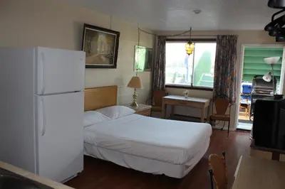 a bedroom with a white bed and a refrigerator at Ritz Inn Niagara in Niagara Falls