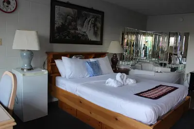 a bedroom with a large white bed and a sink at Ritz Inn Niagara in Niagara Falls