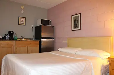 a bedroom with a bed and a refrigerator at Ritz Inn Niagara in Niagara Falls