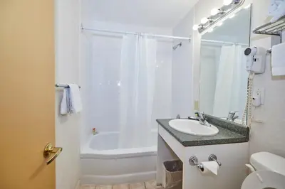 a bathroom with a sink and a tub and a toilet at The Glengate Hotel & Suites in Niagara Falls