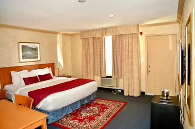 a hotel room with a large bed and a table at The Glengate Hotel & Suites in Niagara Falls