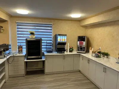 a kitchen with white cabinets and a window at The Glengate Hotel & Suites in Niagara Falls