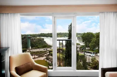 a room with a window with a chair and a view at Sheraton Fallsview Hotel in Niagara Falls