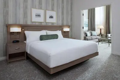 a bedroom with a large white bed and a living room at Delta Hotels by Marriott London Armouries in London