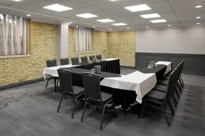 a conference room with black tables and black chairs at Delta Hotels by Marriott London Armouries in London