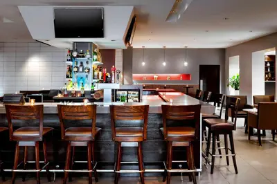 a bar in a restaurant with chairs and a tv at Four Points by Sheraton Mississauga Meadowvale in Mississauga