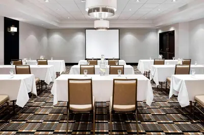 a conference room with white tables and chairs and a projection screen at Four Points by Sheraton Mississauga Meadowvale in Mississauga