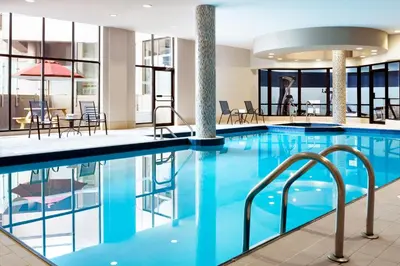 a pool in a hotel with tables and chairs at Four Points by Sheraton Mississauga Meadowvale in Mississauga