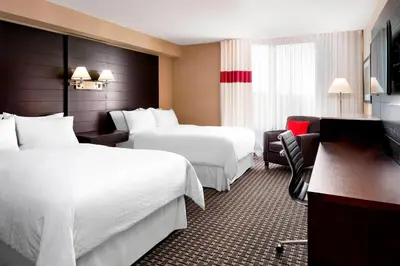 a hotel room with two beds and a desk at Four Points by Sheraton Mississauga Meadowvale in Mississauga