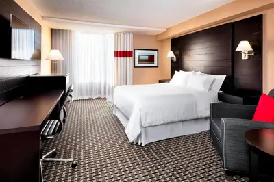 a hotel room with a white bed and a desk at Four Points by Sheraton Mississauga Meadowvale in Mississauga