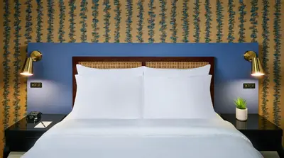 a bedroom with a bed with a blue head board at Hotel Victoria in Toronto