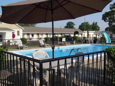 a swimming pool with an umbrella and chairs at Falcon Inn in Niagara Falls