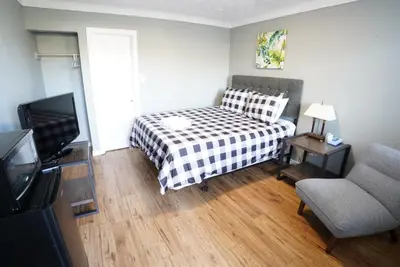 a bedroom with a bed and a chair and a television at Falcon Inn in Niagara Falls
