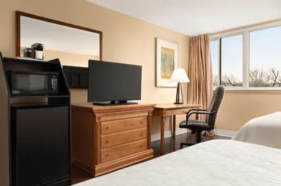 a hotel room with a television on a dresser with a bed at Travelodge by Wyndham Richmond Hill in Richmond Hill