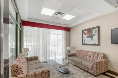 a living room with a couch and chairs and a window at Best Western Plus Travel Hotel Toronto Airport in Toronto