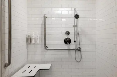 a white tiled bathroom with a shower and a toilet at Spark by Hilton Toronto Airport in Toronto