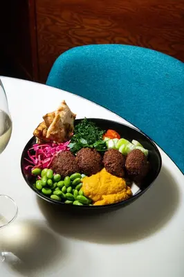 a plate of food with meatballs and vegetables on a table at The Drake Hotel in Toronto