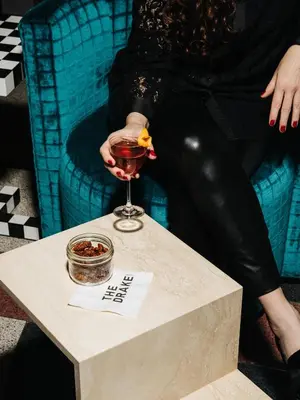 a woman holding a glass of wine on a table at The Drake Hotel in Toronto