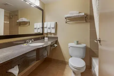a bathroom with a toilet and a sink and a mirror at Best Western Plus Burlington Inn & Suites in Burlington