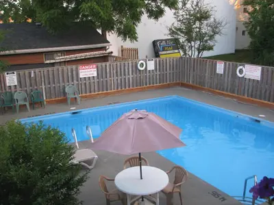 a table with an umbrella next to a swimming pool at Sunset Inn in Niagara Falls