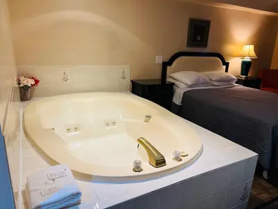 a bath tub in a room with a bed at Sunset Inn in Niagara Falls