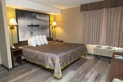 a hotel room with a bed and a painting of a boat at Super 8 by Wyndham Mississauga in Mississauga