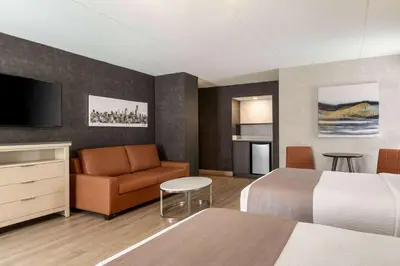 a hotel room with a bed and a couch and a television at Days Inn by Wyndham Toronto West Mississauga in Mississauga