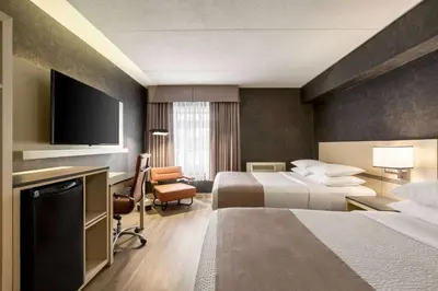 a hotel room with two beds and a flat screen tv at Days Inn by Wyndham Toronto West Mississauga in Mississauga