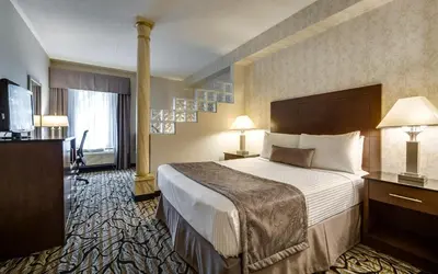a hotel room with a bed and a television at Monte Carlo Inn Oakville Suites in Oakville