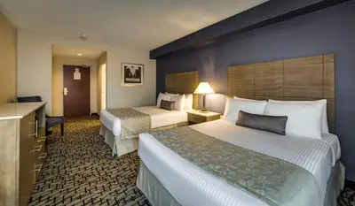 a hotel room with two beds and a desk at Monte Carlo Inn Oakville Suites in Oakville